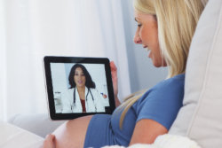 Pregnant woman talking to her doctor on tablet
